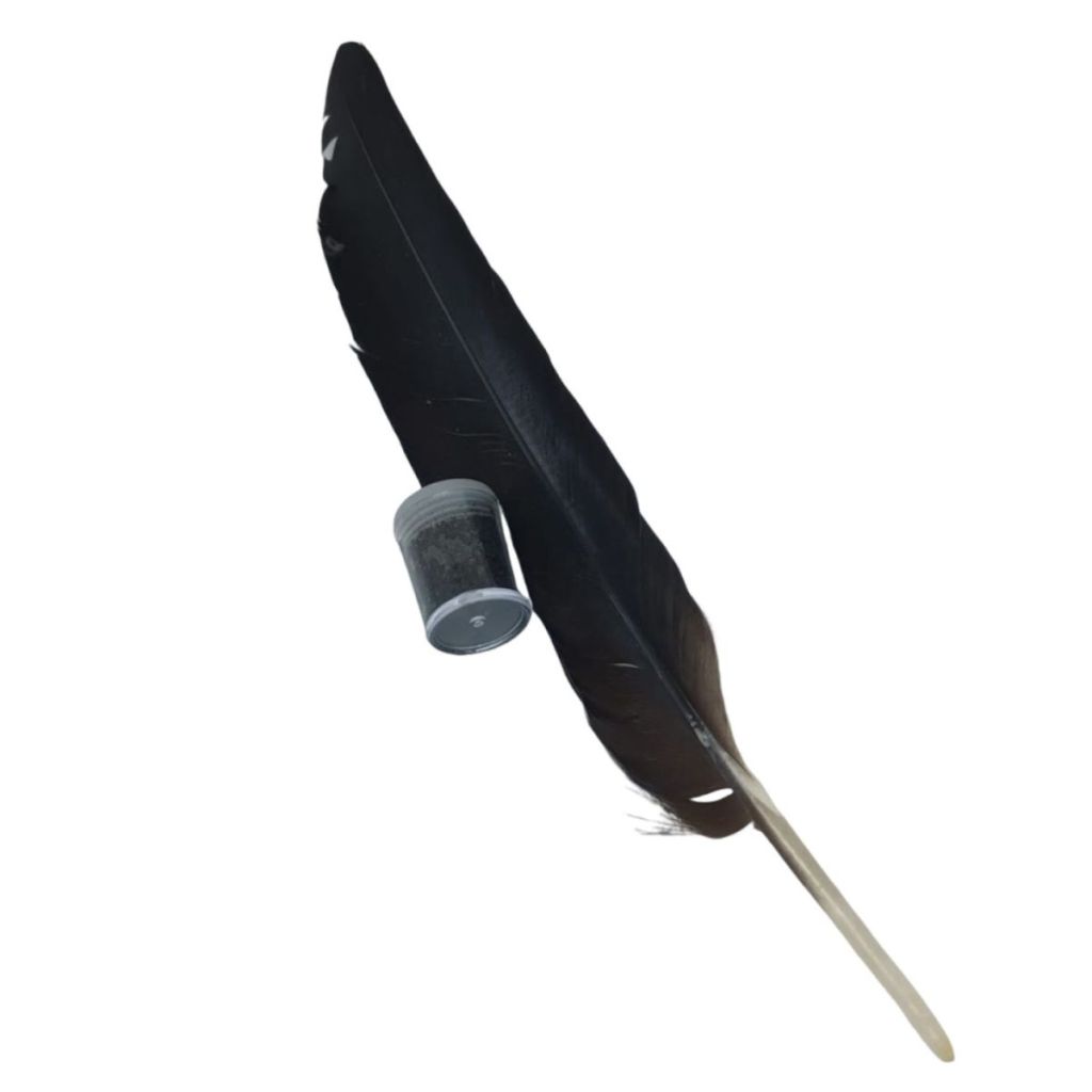 Pó de Pena de Urubu em pote transparente ao lado de uma pena preta, usado em simpatias para combater o vício do álcool.